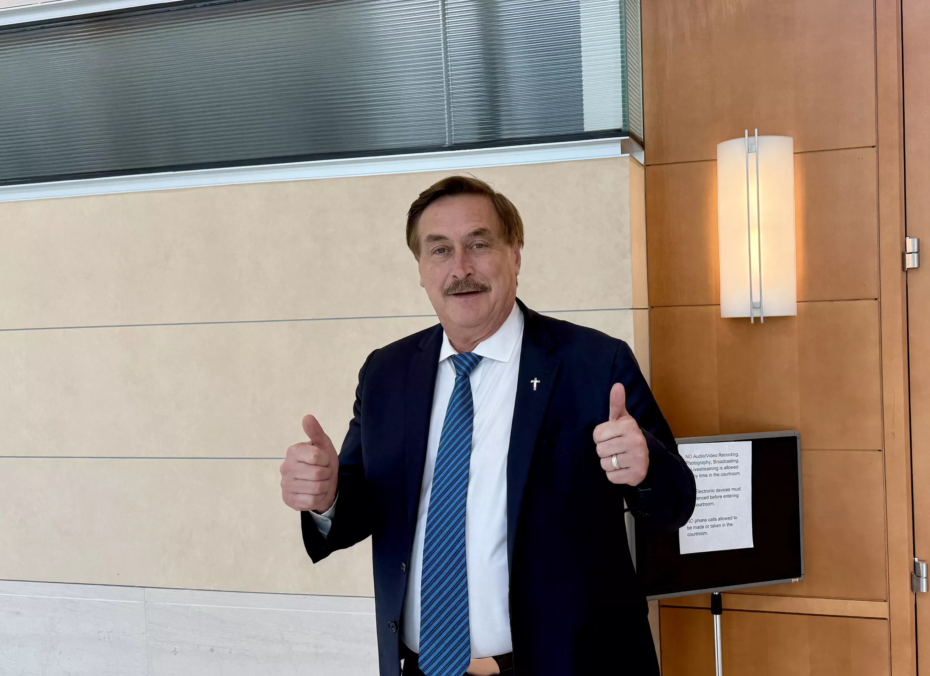 MyPillow CEO Mike Lindell puts two thumbs up outside the courtroom where he's being sued for defamation