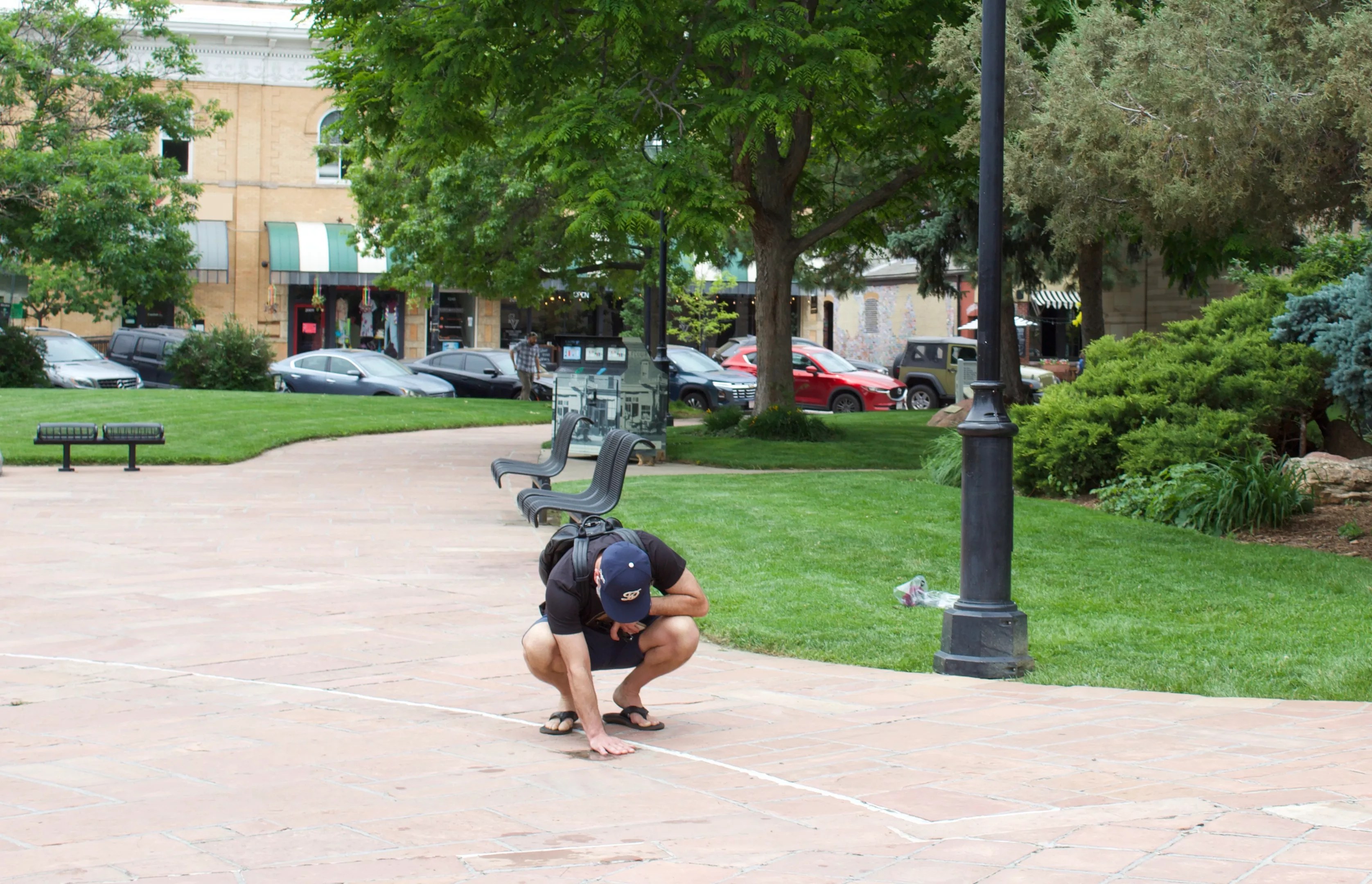 Man kneels down on sidewalk