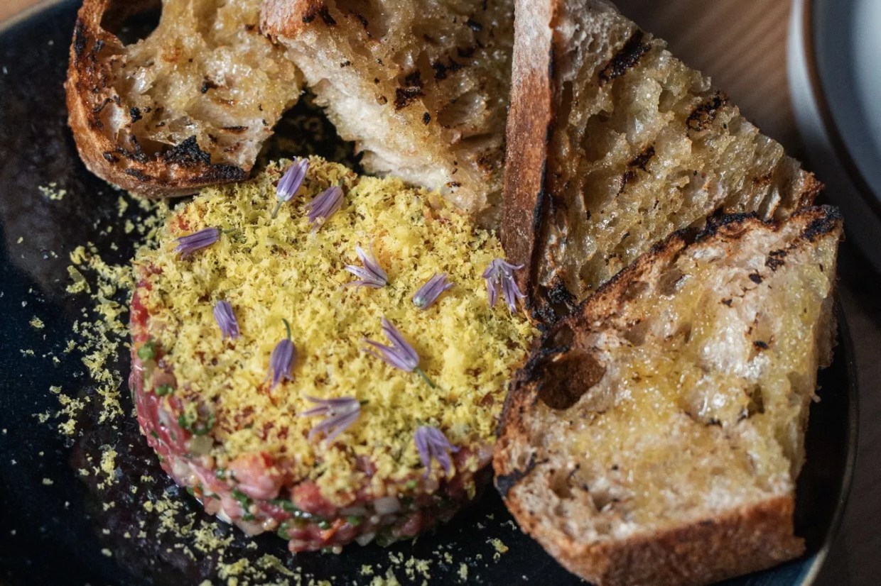 Wagyu steak tartare garnished with edible flowers and served with grilled bread