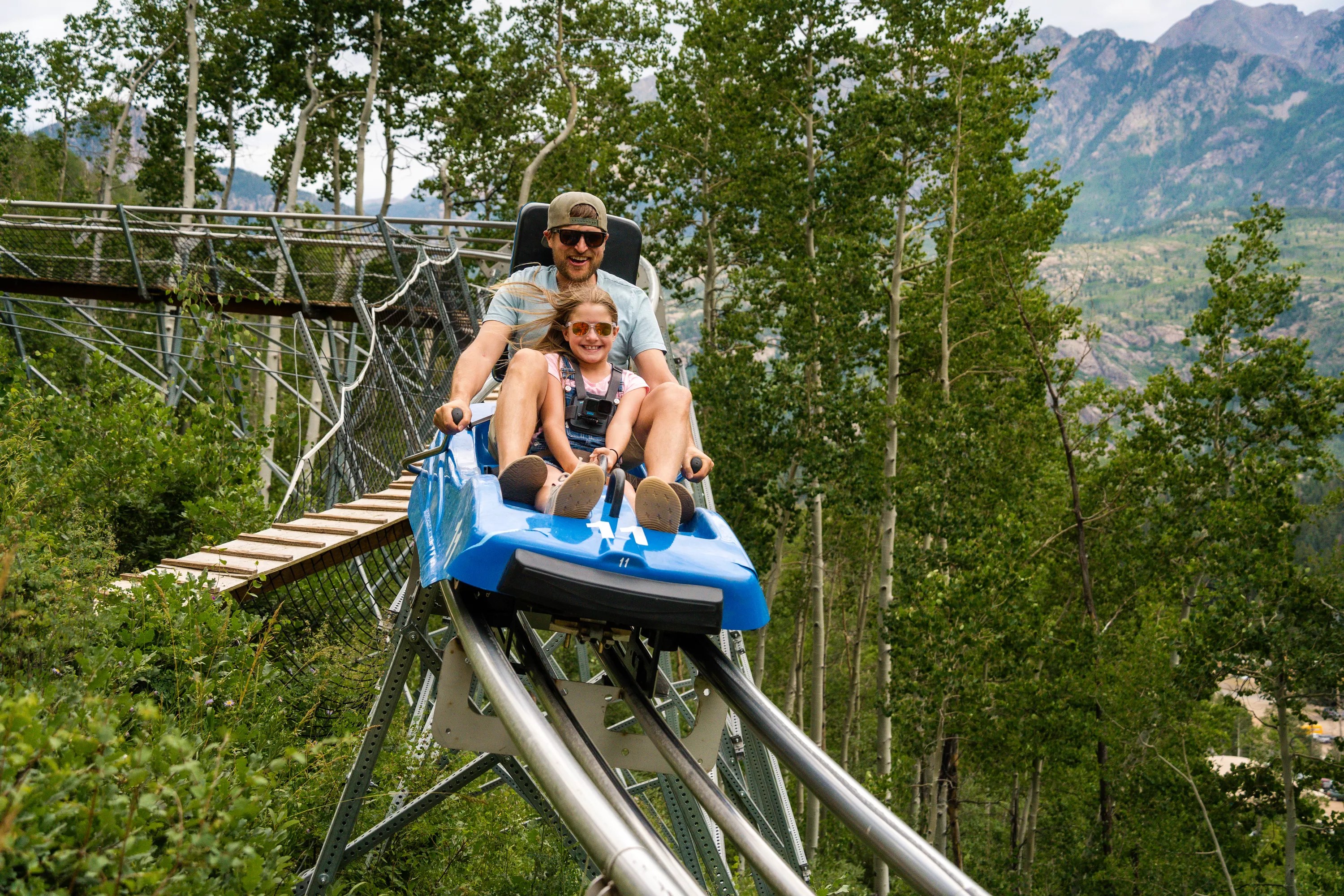 A man and young girl riding the mountain coaster at Purgatory Resort