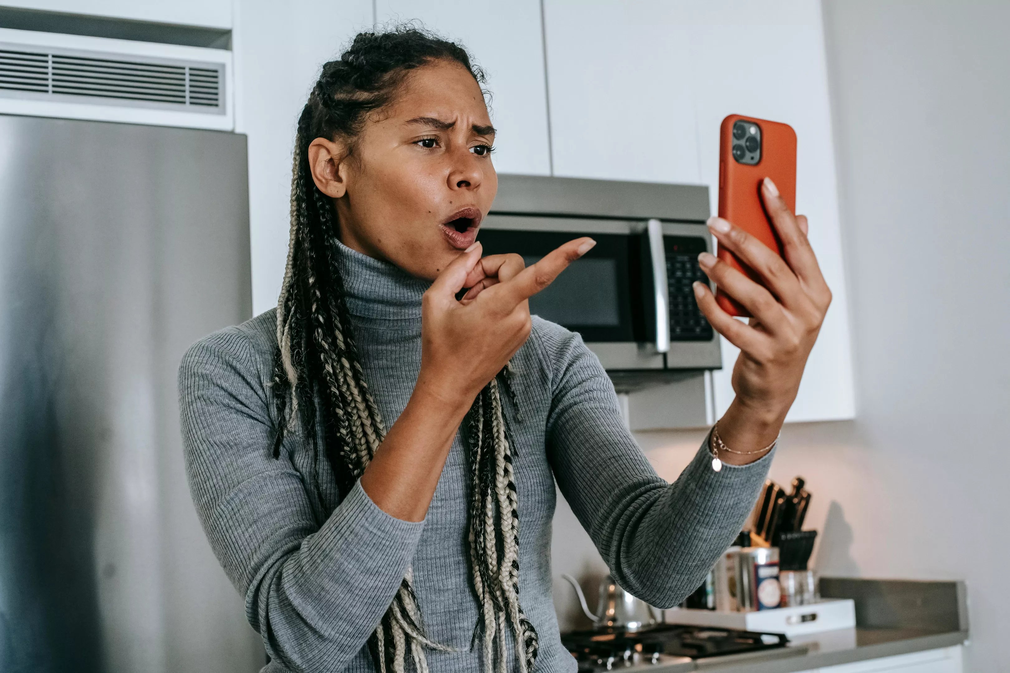 a woman pointing at a phone indignantly