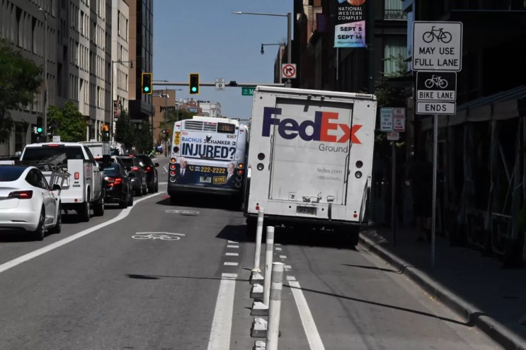 A truck and a bus block a bike lane.
